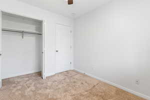 Unfurnished bedroom featuring light colored carpet, a closet, and ceiling fan