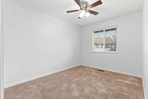 Carpeted spare room featuring baseboards and ceiling fan