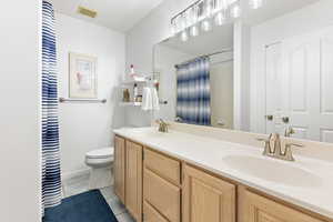 Full bathroom featuring double vanity, light tile patterned floors, and a shower with curtain