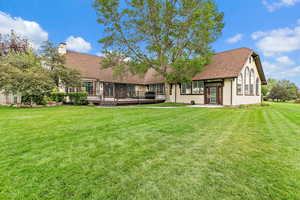 Back of property featuring roof with shingles, a lawn, a chimney, a deck, and a patio