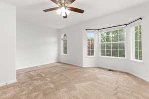 Carpeted spare room with baseboards and a ceiling fan