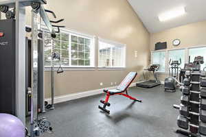 Workout area with high vaulted ceiling and baseboards