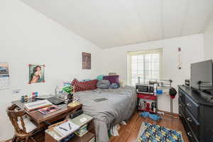 Bedroom with wood finished floors and lofted ceiling