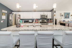 Kitchen featuring a kitchen bar, stainless steel appliances, and white cabinets