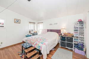 Bedroom with light wood-type flooring and vaulted ceiling