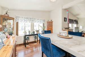 Dining area with light wood finished floors and lofted ceiling