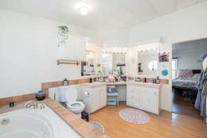 Ensuite bathroom with vanity, a jetted tub, and light wood-type flooring
