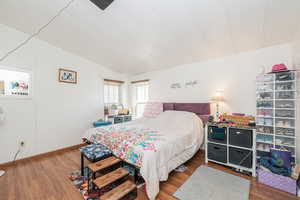 Bedroom featuring wood finished floors and lofted ceiling