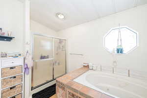 Full bathroom featuring a stall shower, a whirlpool tub, and vaulted ceiling