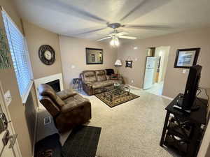 Carpeted living room featuring a textured ceiling and ceiling fan