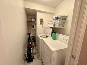 Washroom with washer and clothes dryer and light tile patterned floors