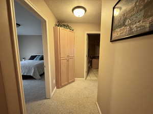 Hall with a textured ceiling and light carpet