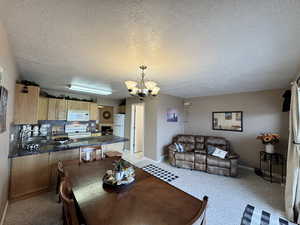 Dining room with a chandelier, a textured ceiling, and light colored carpet