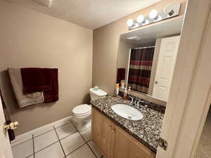 Bathroom with vanity, a textured ceiling, light tile patterned floors, and a shower with shower curtain