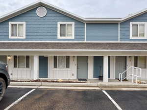View of front facade with covered porch, board and batten siding, and uncovered parking
