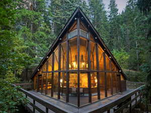 Rear view of property featuring a view of trees and a sunroom