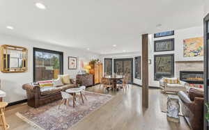 Living area featuring light wood-style flooring, recessed lighting, and a glass covered fireplace