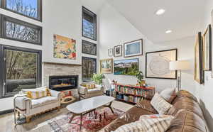 Sitting room with hardwood / wood-style flooring, recessed lighting, a high ceiling, and a glass covered fireplace