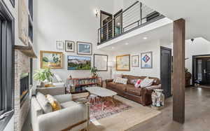 Living room featuring a high ceiling, wood finished floors, a stone fireplace, and recessed lighting