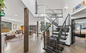 Stairway featuring wood finished floors, recessed lighting, and a towering ceiling