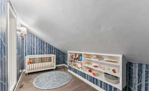 Playroom with carpet flooring, wallpapered walls, and vaulted ceiling