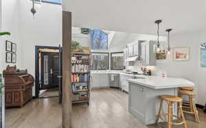 Kitchen with a peninsula, light countertops, a breakfast bar, light wood-style flooring, and gray cabinets