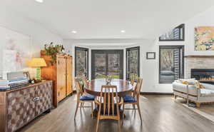 Dining space with wood finished floors, a glass covered fireplace, and recessed lighting