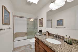 Full bathroom featuring shower / bath combination with glass door, vanity, a skylight, and light tile patterned floors