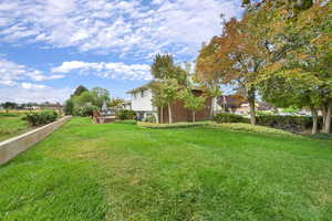 View of green lawn featuring a wooden deck