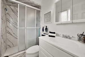 Bathroom with vanity and a marble finish shower