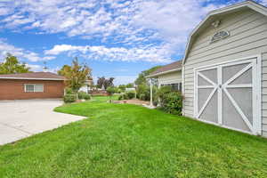View of green lawn featuring an outbuilding