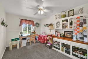 Home office featuring dark carpet, a textured ceiling, and a ceiling fan