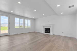 Unfurnished living room featuring recessed lighting, light wood-style floors, and a glass covered fireplace