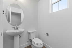 Half bathroom featuring toilet and wood finished floors