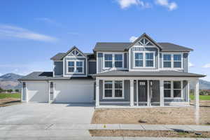 View of front of property featuring a mountain view, concrete driveway, and roof with shingles