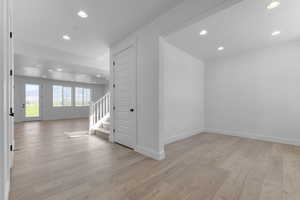 Unfurnished room featuring recessed lighting, light wood-style floors, and stairway