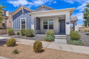View of front of home featuring a porch, a tiled roof, board and batten siding, and stone siding