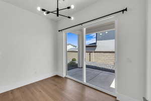 Empty room with wood finished floors and a chandelier