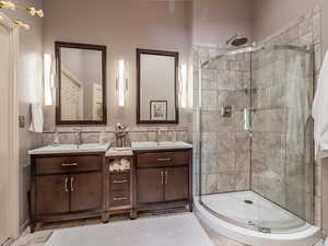Bathroom with a stall shower, double vanity, tile walls, and light tile patterned flooring