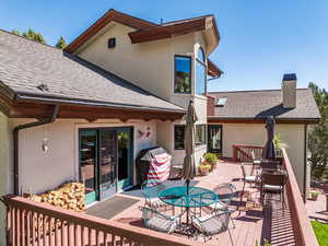 Back of house featuring outdoor dining space, a shingled roof, a deck, stucco siding, and a chimney