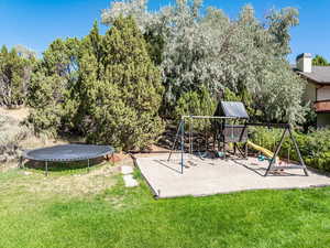 View of play area featuring a yard, a trampoline, and view of wooded area