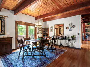 Dining room with a chandelier, wood finished floors, and a wooden ceiling with exposed beams