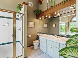 Bathroom featuring vanity, a stall shower, light tile patterned floors, and a textured wall