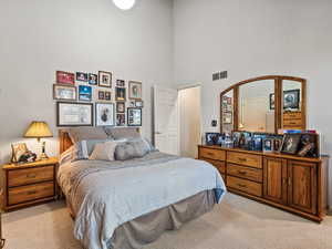 Bedroom with light colored carpet and a towering ceiling
