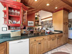 Bar area featuring dishwasher, dark stone counters, wooden ceiling, a ceiling fan, and light tile patterned floors