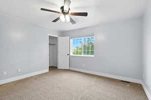 Unfurnished bedroom with light colored carpet, a closet, and a ceiling fan