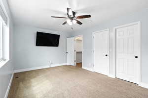 Unfurnished bedroom with a spacious closet, carpet floors, and a ceiling fan