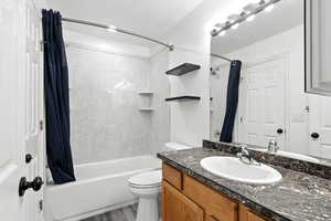 Full bathroom with shower / bathtub combination with curtain, vanity, light wood-style floors, and a textured ceiling