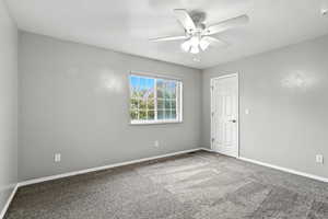 Carpeted empty room featuring baseboards and a ceiling fan