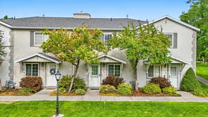 Traditional-style house featuring a front yard, roof with shingles, and stucco siding